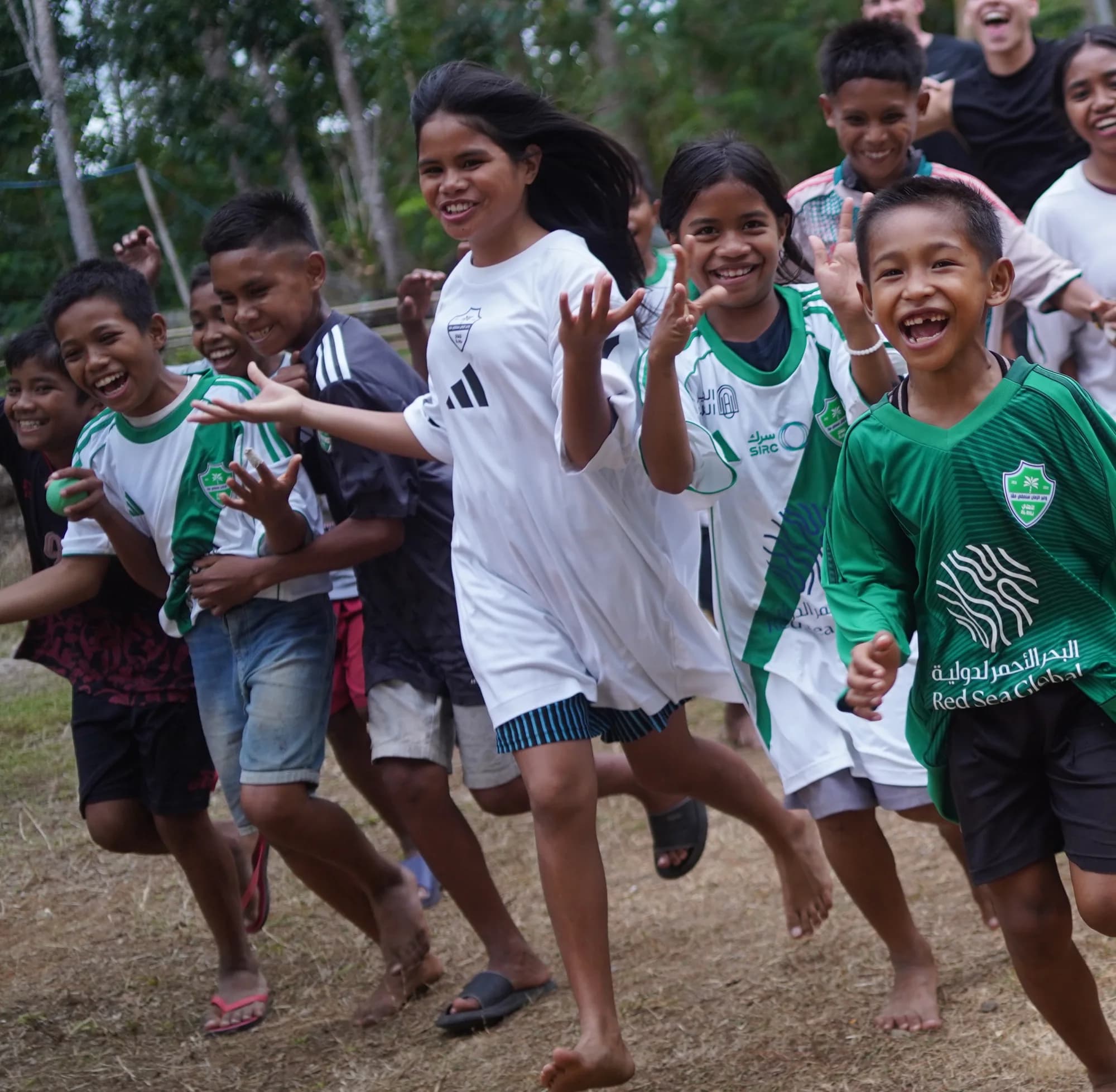 Children running toward the camera, laughing, in a village in Sumba.